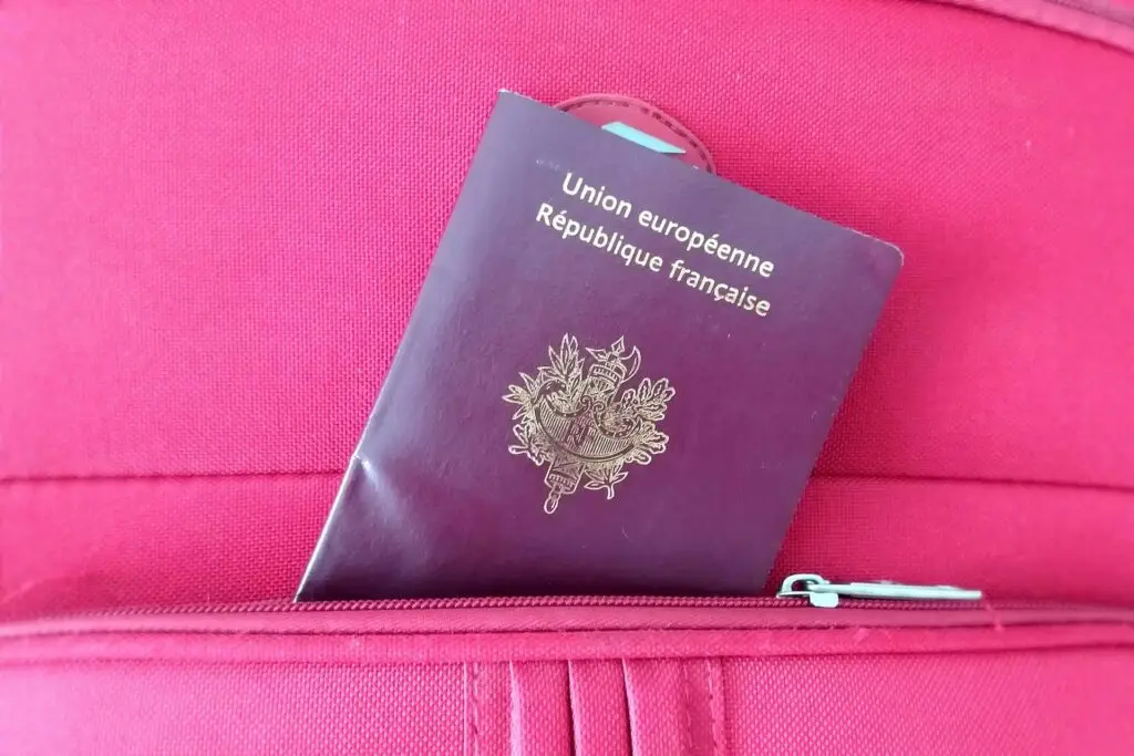 Photo d'une valise avec un passeport français glissé dans une poche